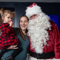 Mom and daughter smile standing next to Santa